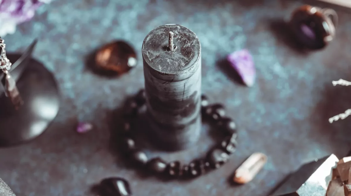 Black candle on a witch's altar for a magical ceremony among crystals and black candles.