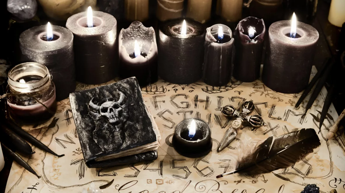 2C3M01P Evil book with black magic spells, candles and ouija board on witch table. Wicca, esoteric and occult background with vintage magic objects for mystic